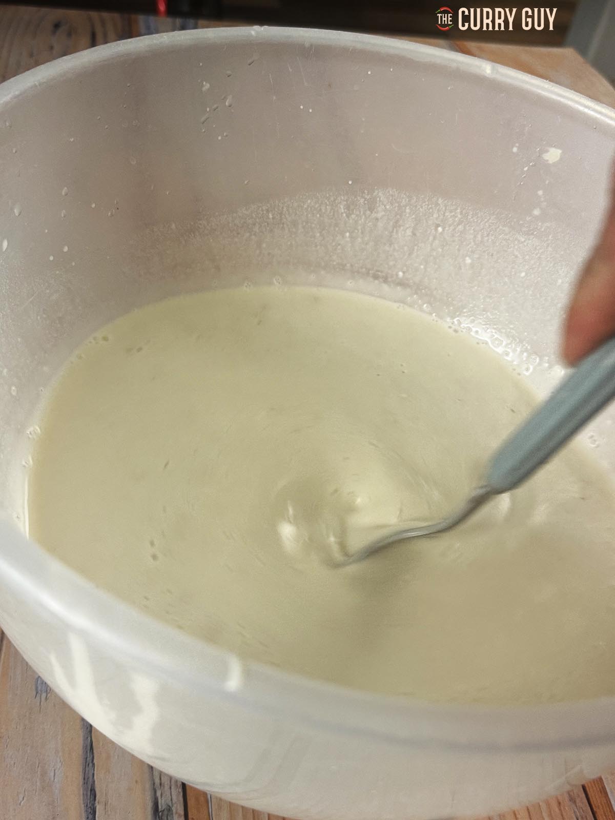 Stirring the dough starter and the water together until smooth.