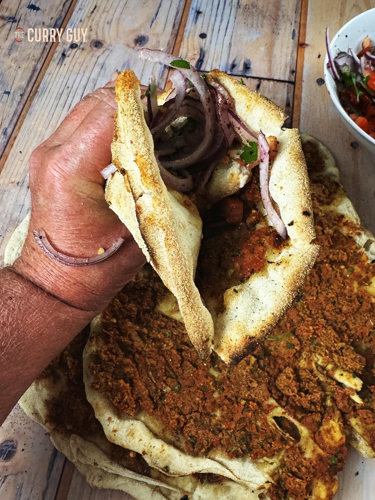 A lahmacun topped with Turkish onion salad and folded in half.