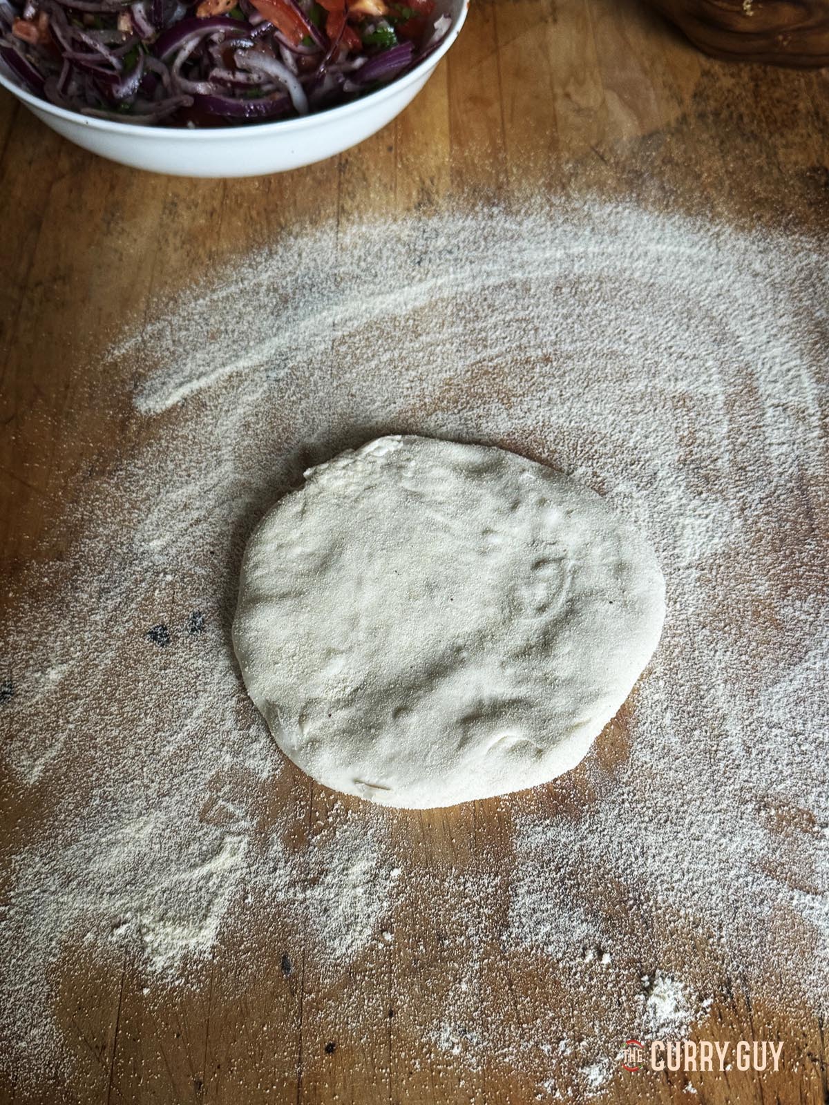 A flattened dough ball ready to roll out thinnly.