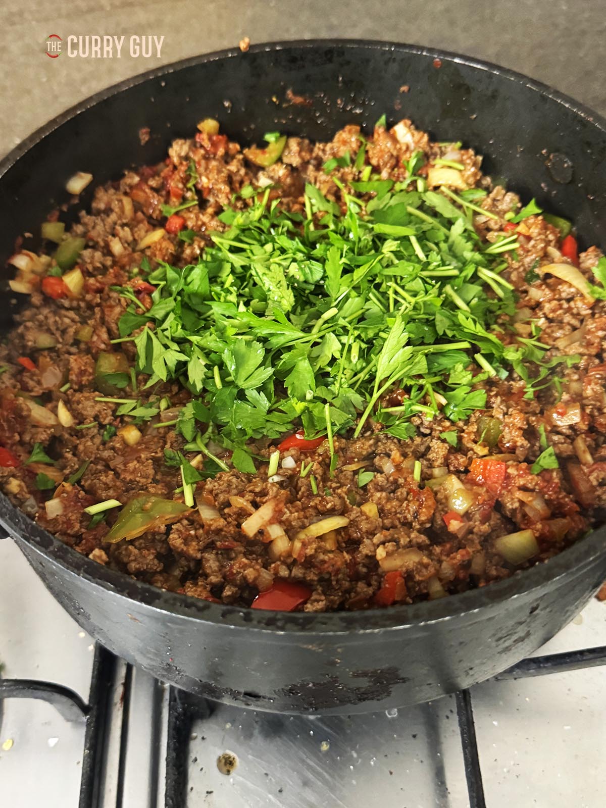 Adding fresh flat leaf parsley to the meat mixture.