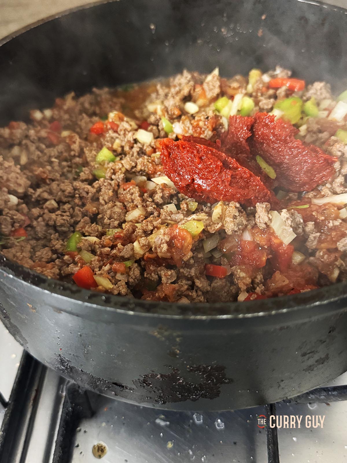 Adding the red pepper paste and the tomato paste to the meat.