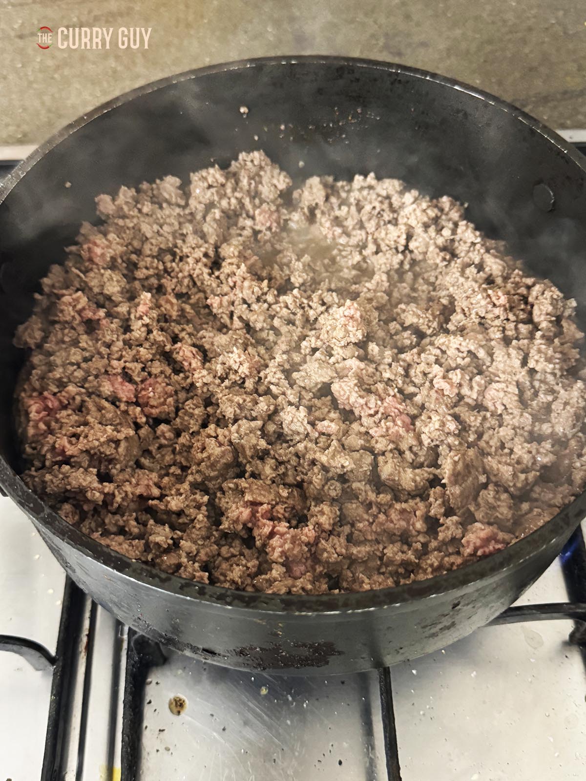 Frying the beef in a pan until cooked through.