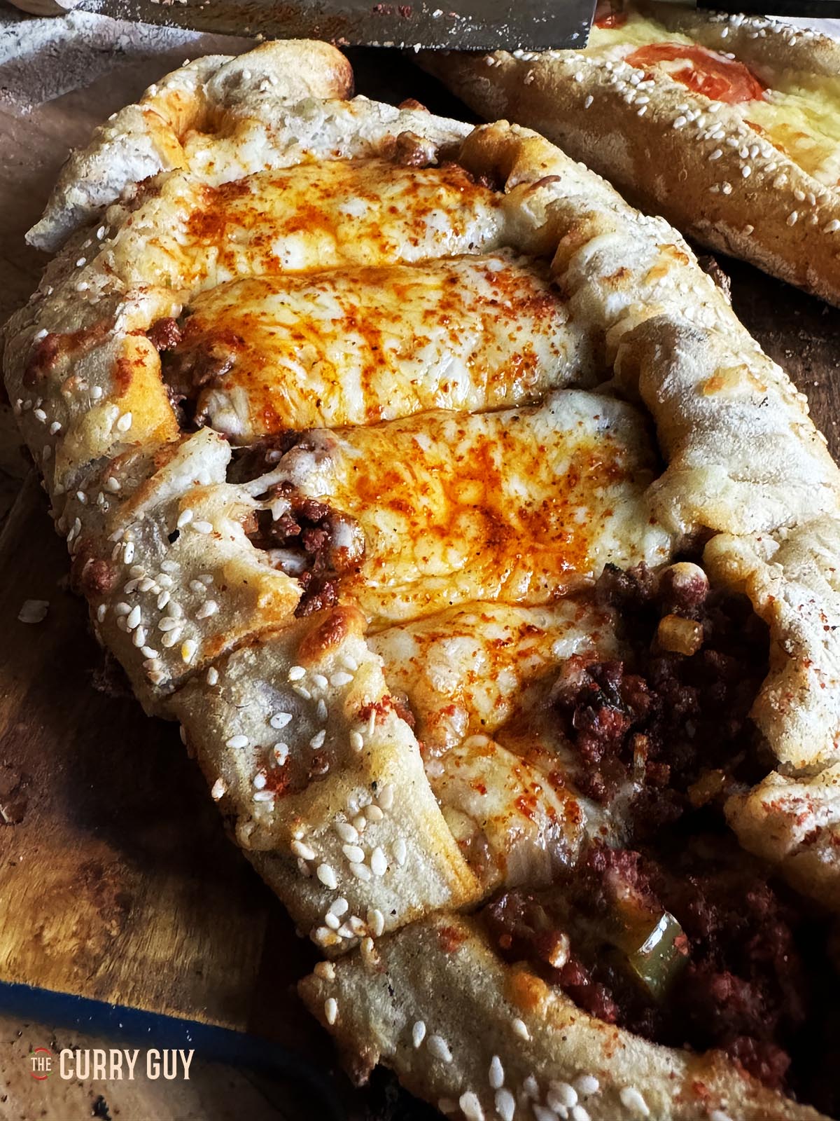 Meat pide covered with cheese melted on top.