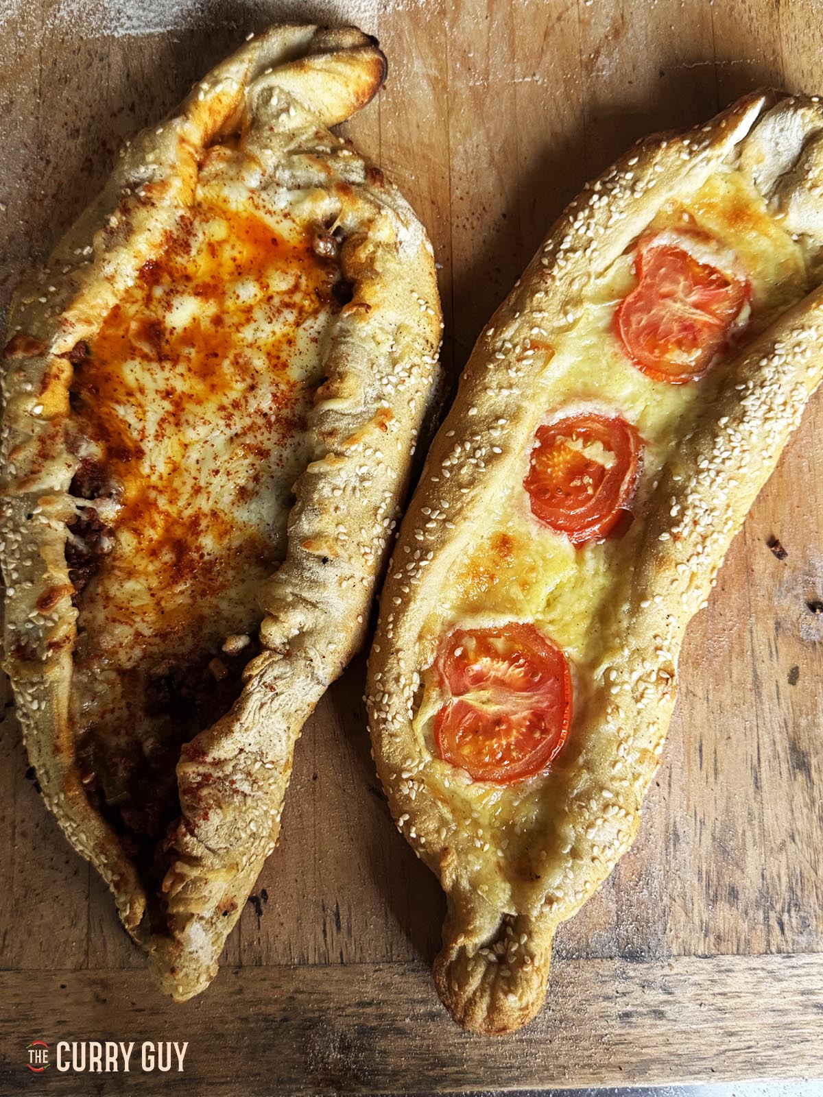 Two pide breads, one filled with meat and cheese and the other with cheese and tomato.