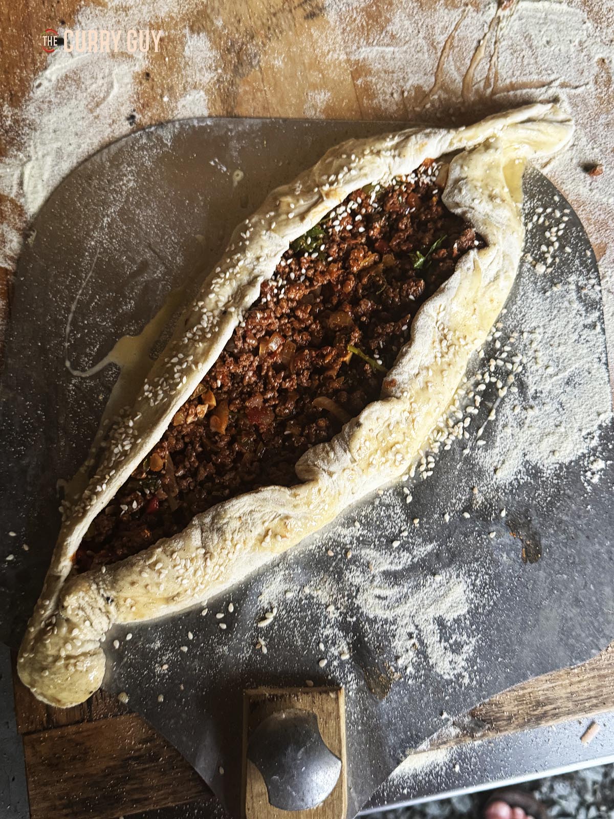 Covering the top of the dough with the meat mixture and folding the dough over the meat to make a boat shape.
