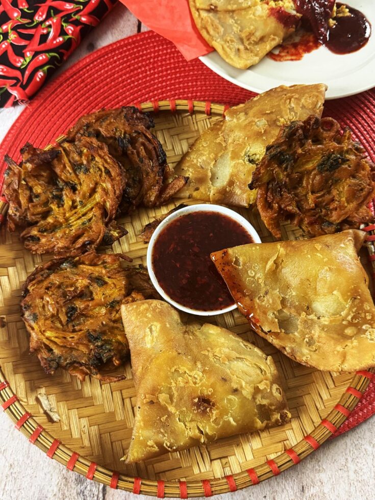 Dipping a samosa into the red samosa sauce.