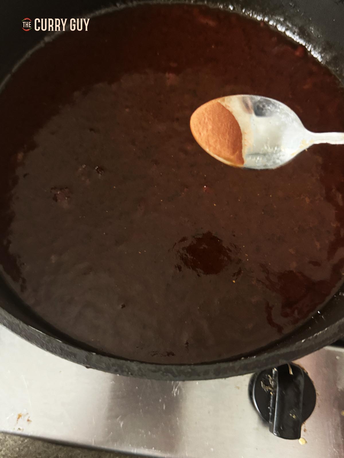 Adding red food colouring to the sauce.