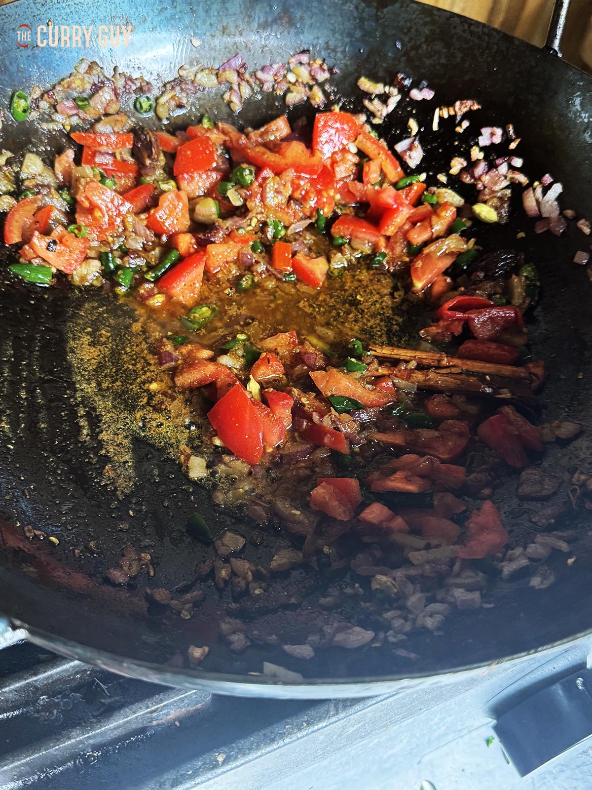 Adding the spices, tomatoes and chopped chillies to the pan.