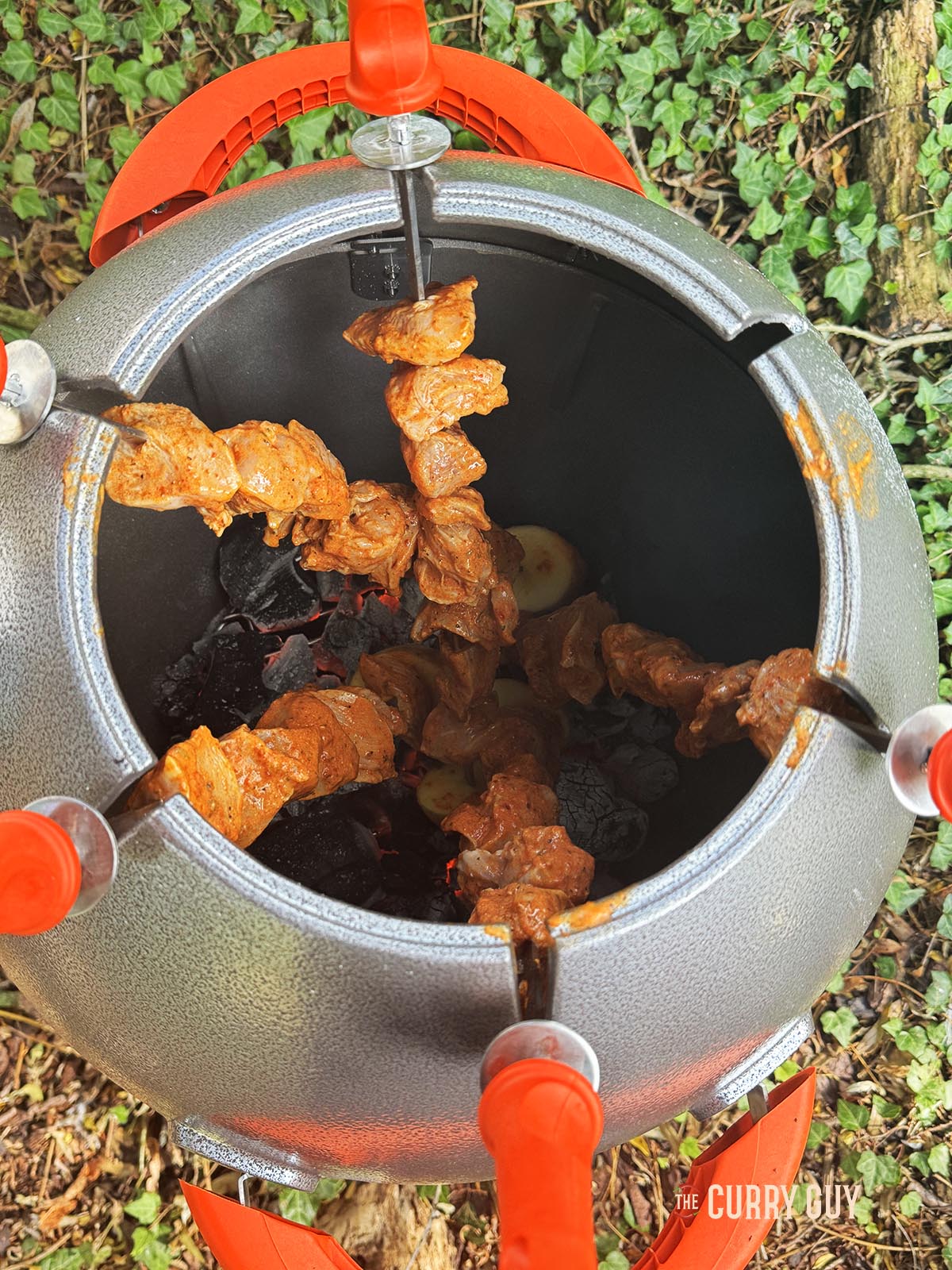 The chicken skewers cooking in a tandoor oven.