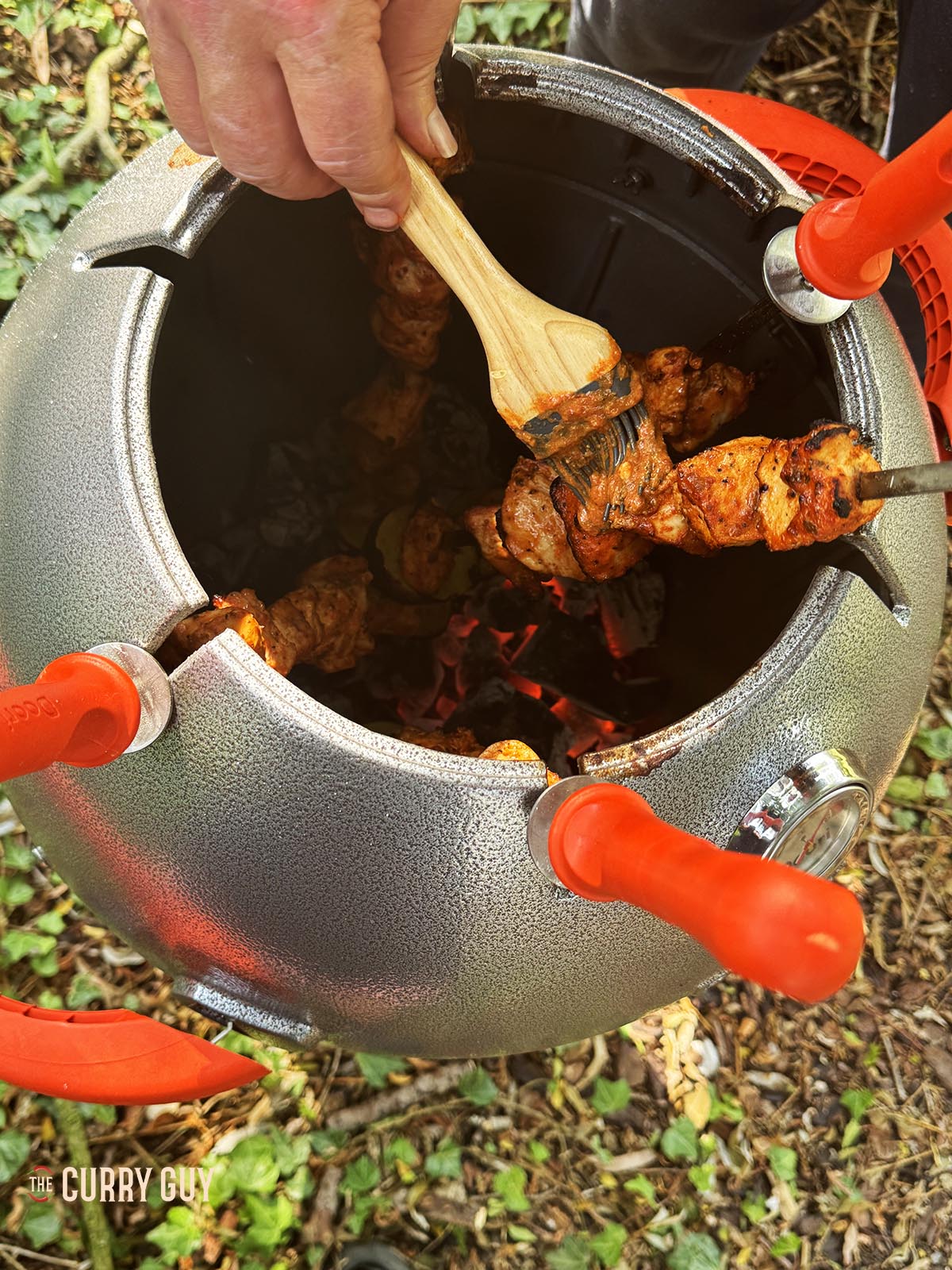 Basting the chicken with marinade as it cooks.