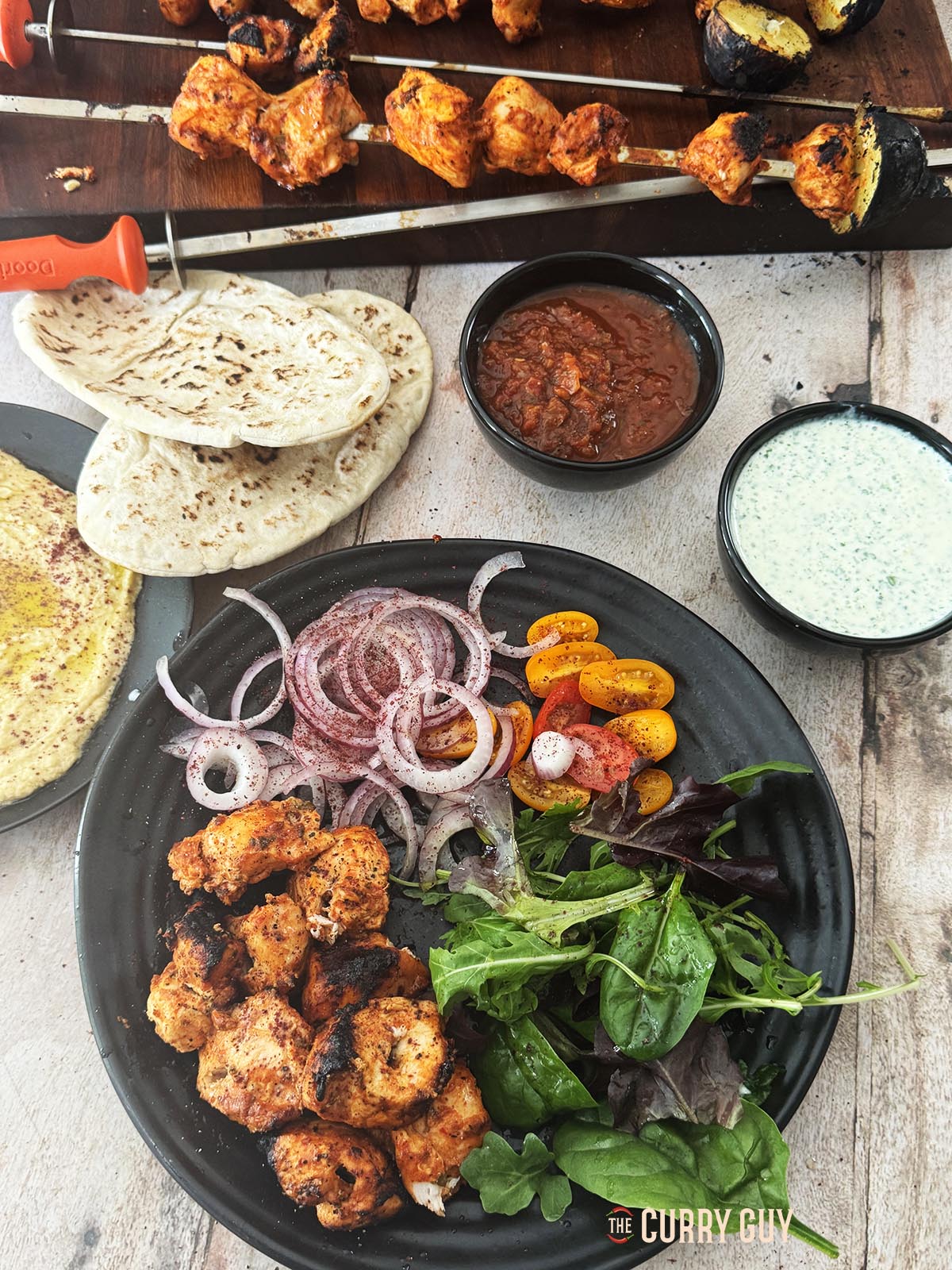 Turkish chicken kabobs on a serving plate with salad and sauces.