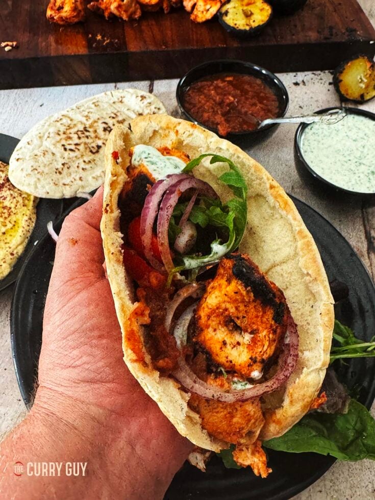 Turkish chicken kabob meat wrapped in a pita with salad and sauces.