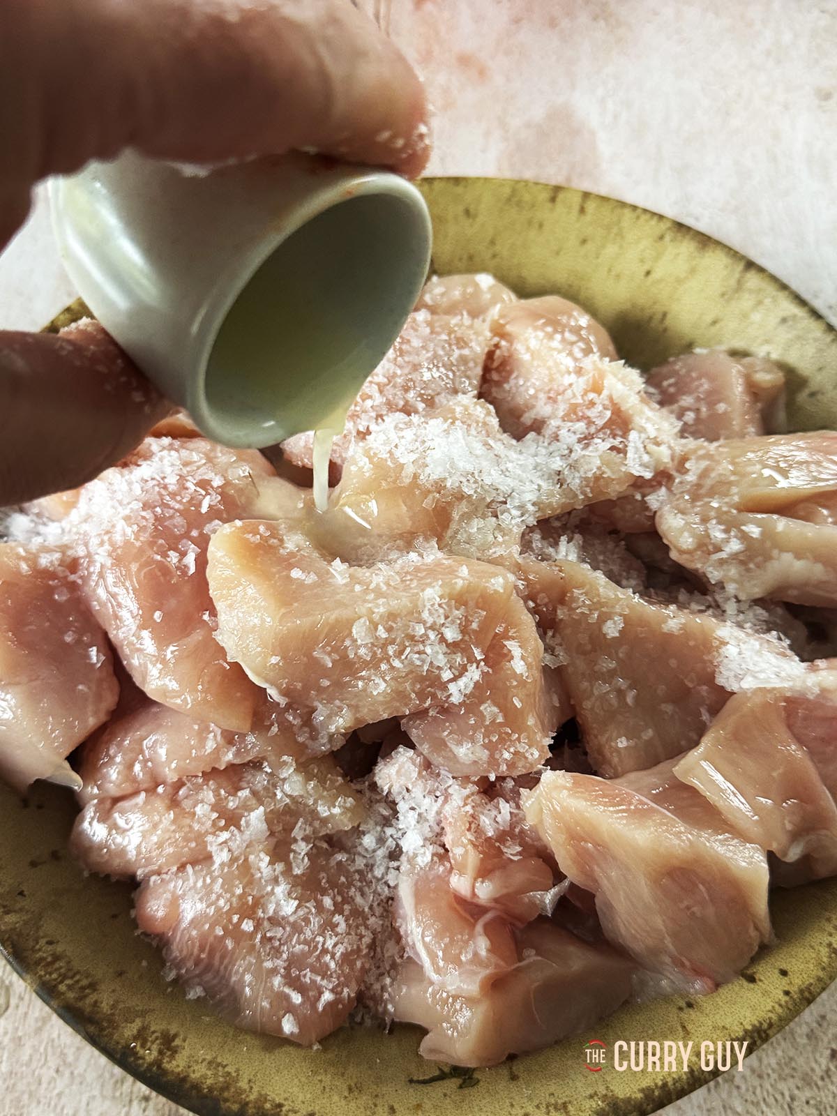 Adding lemon juice and salt to the chicken pieces in a mixing bowl.