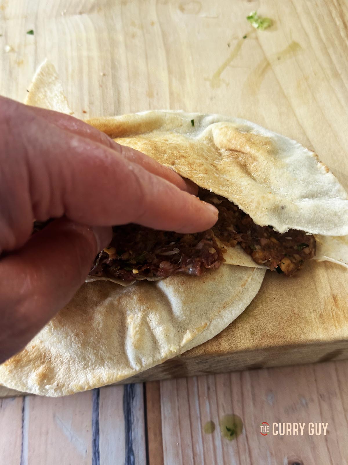 Pressing the meat over the bottom layer of the pita.