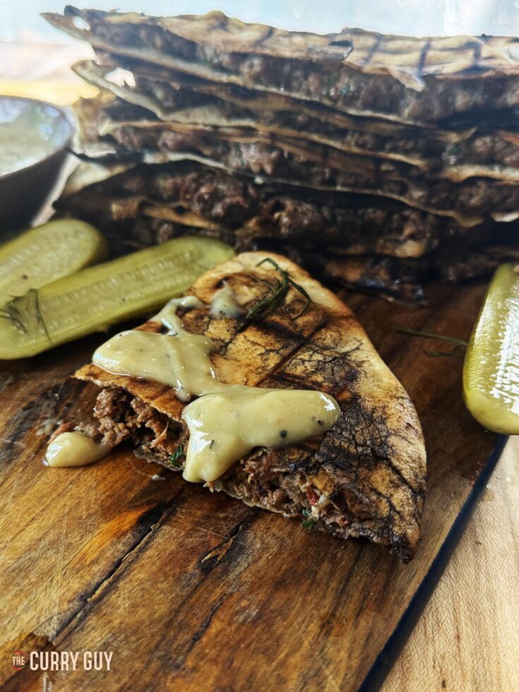 Areyes - Meat stuffed pitas on a serving platter with tahini sauce.