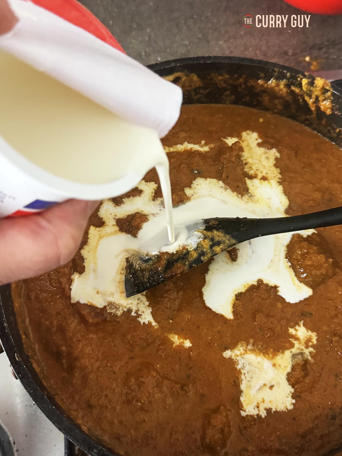 Pouring the cream into the curry.