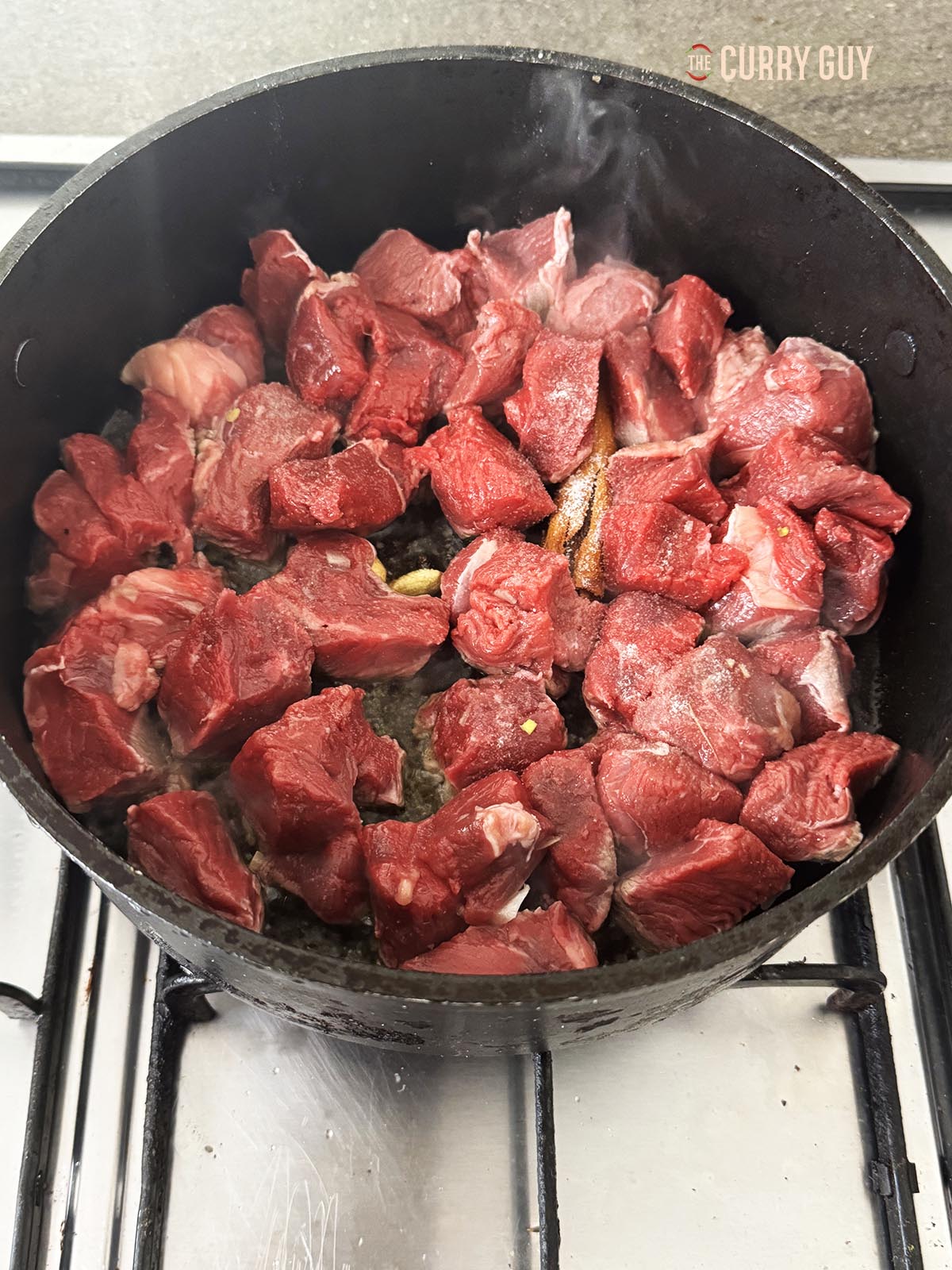 Adding the cubed beef to the pan.