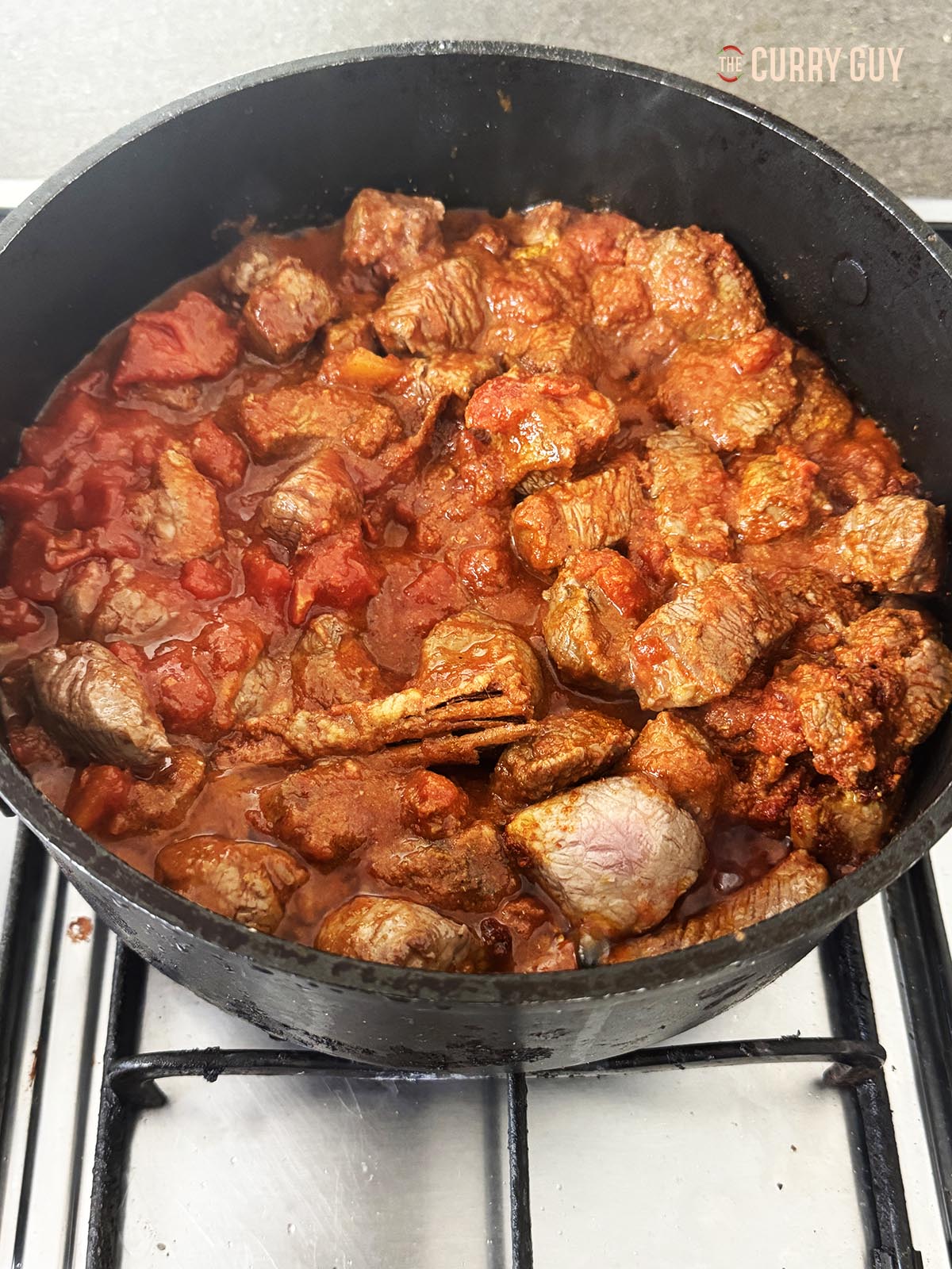 Adding the spices, chopped tomatoes and blended onions and chillies to the pan.