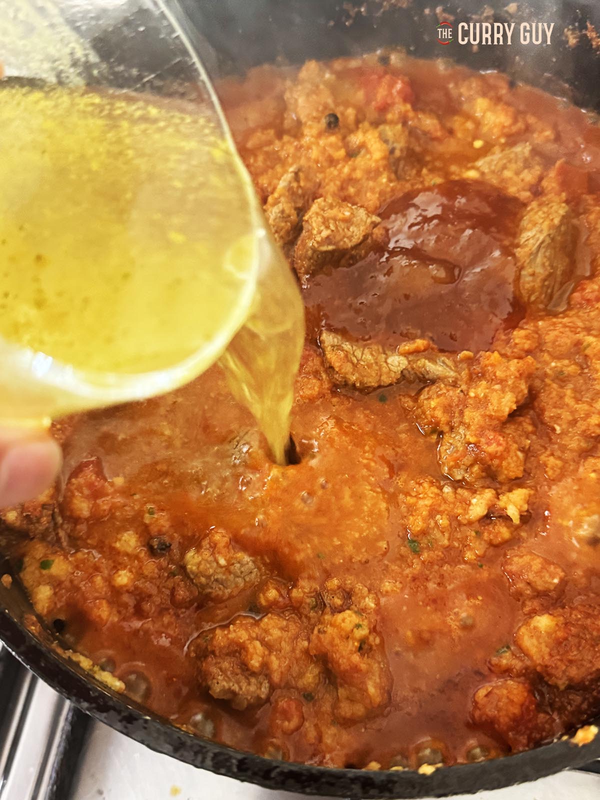 Adding the stock and mango chutney to the pan.