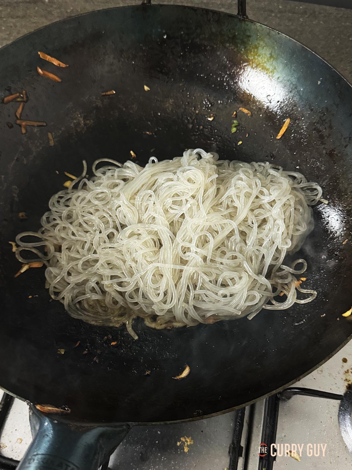 Adding the noodles to the wok.