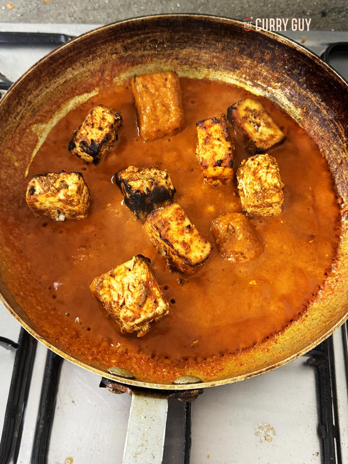 Adding the paneer to the sauce in the pan.