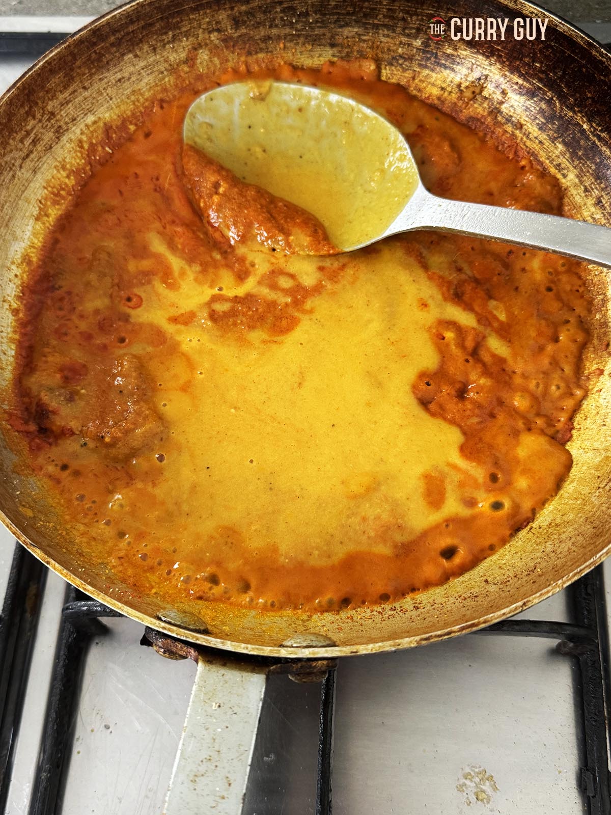 Adding more base sauce to the pan.