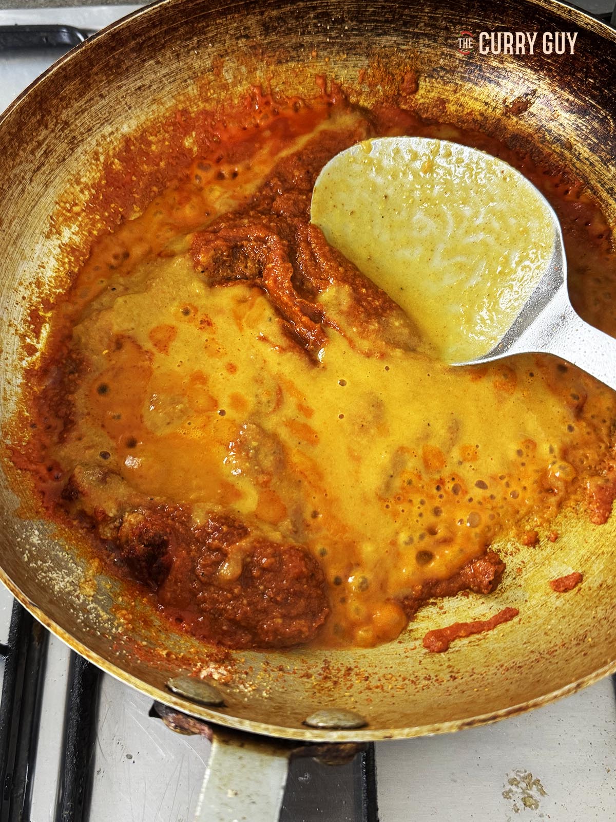 Adding a ladle of the base sauce to the pan.
