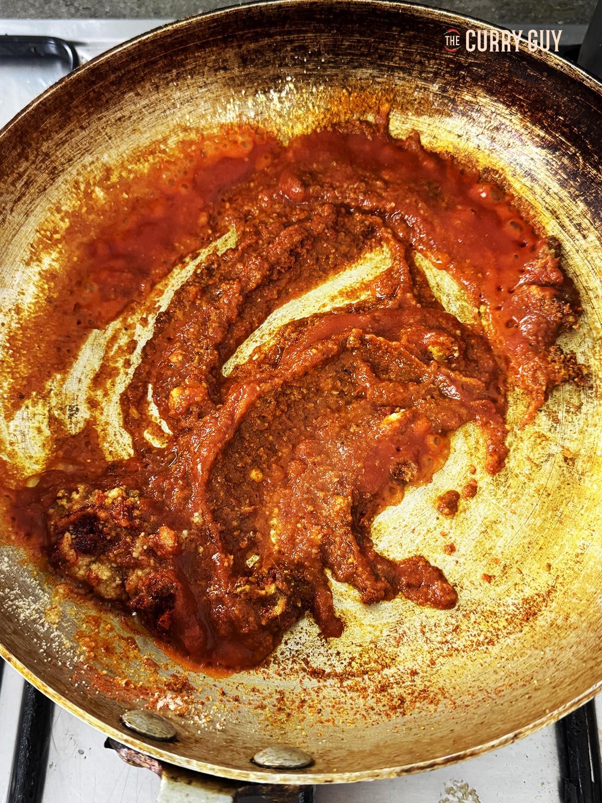 Adding the passata to the pan and stirring it into the spices.