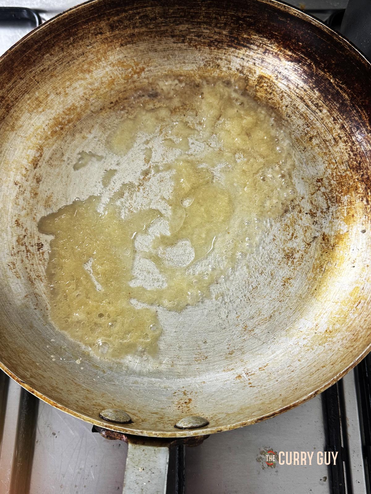 Frying the garlic and ginger paste in oil in a pan.