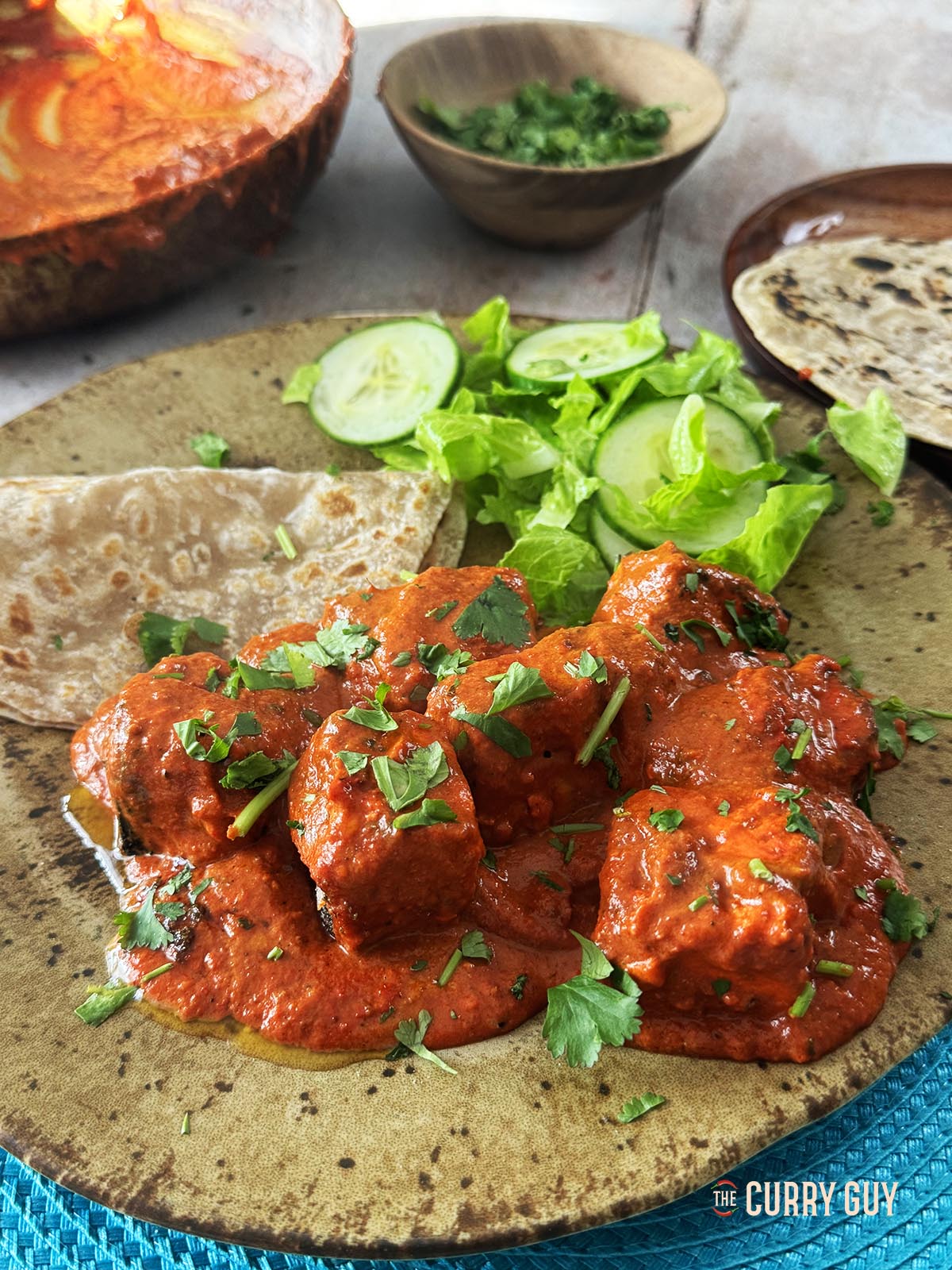 Serving the paneer tikka masala on a serving plate with chapatti and garnished with chopped coriander (cilantro).