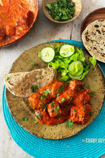 Paneer tikka masala on a serving plate with side dishes.