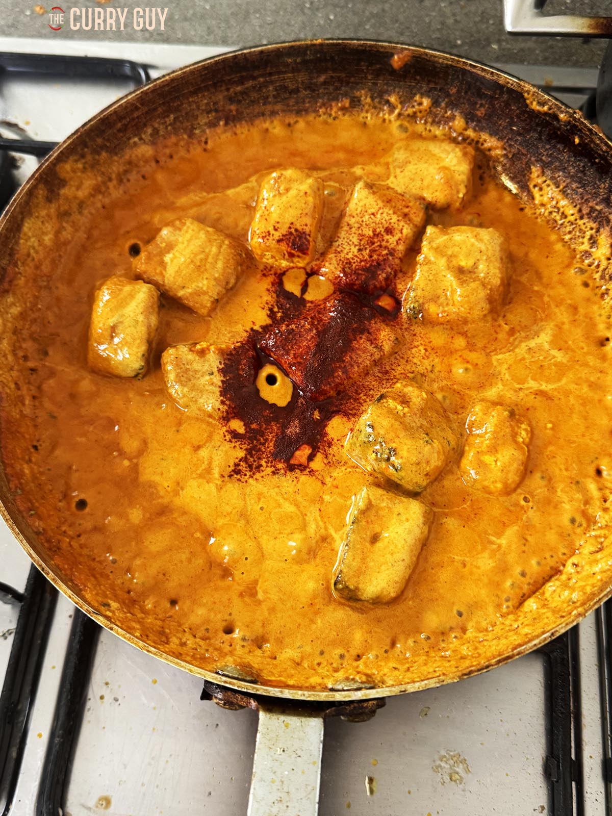 Adding red food colouring powder to the curry.