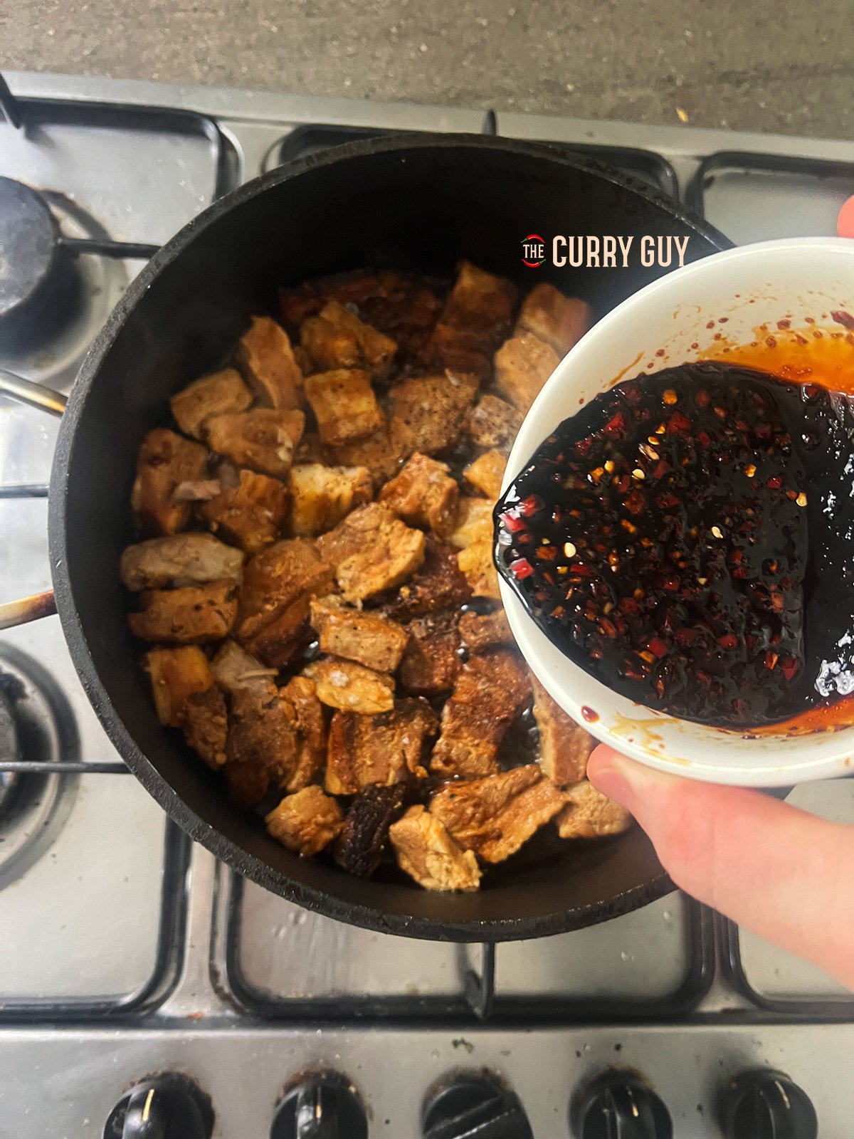 pouring the sticky sauce on the pork belly