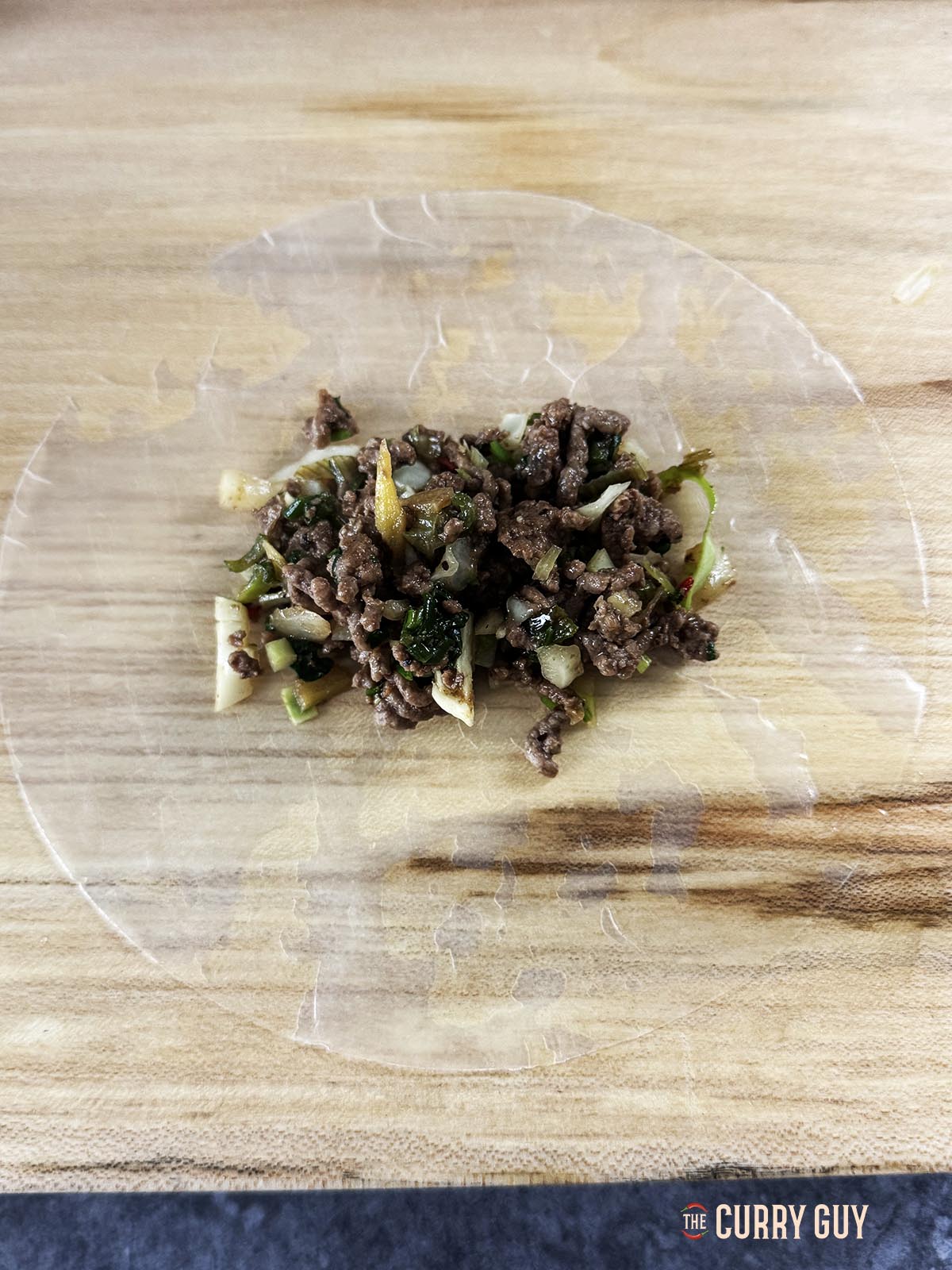 Placing a spoonful of the meat mixture on a soaked rice paper round.