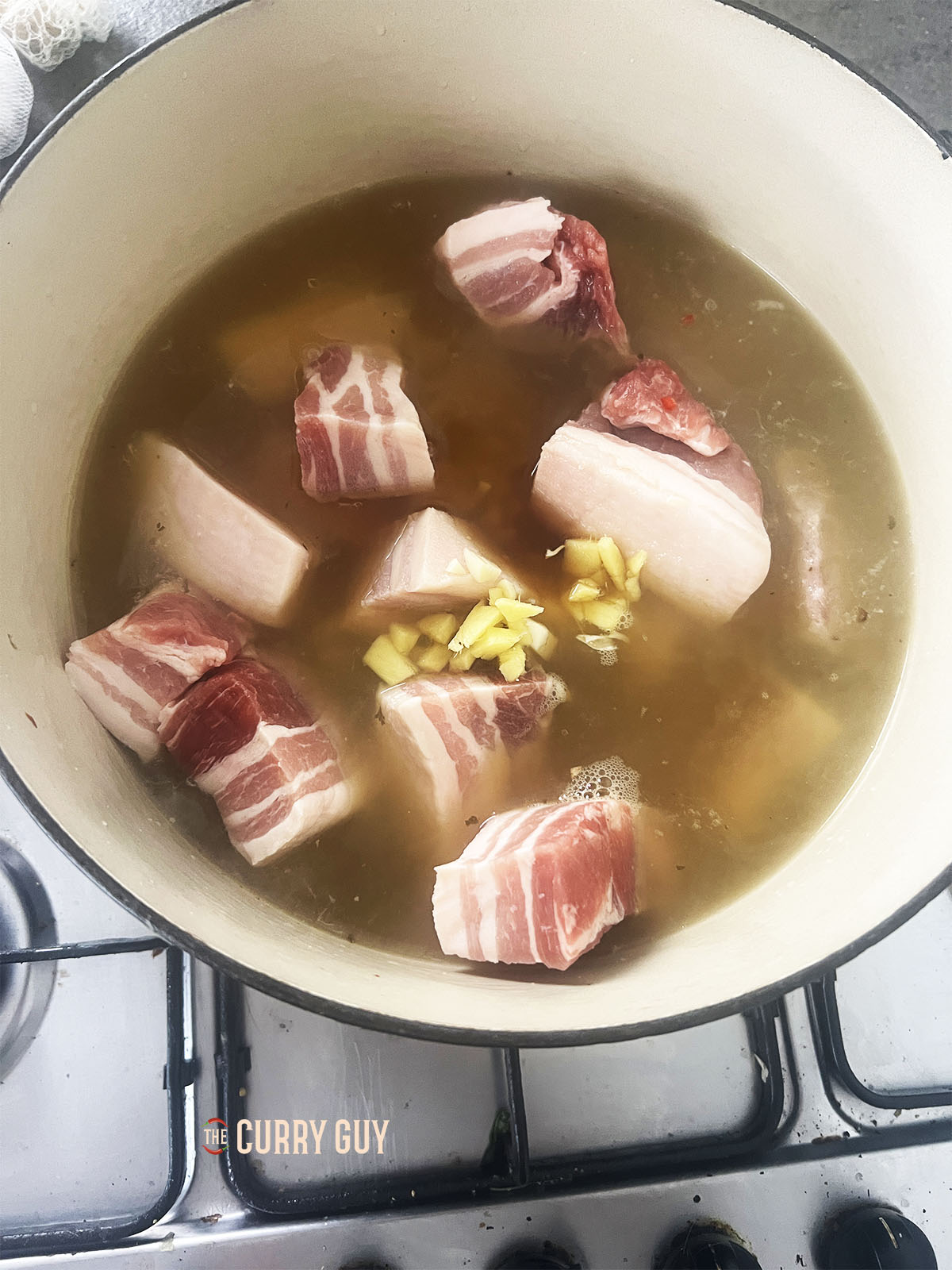 The pork belly in the stock with spices ready to boil