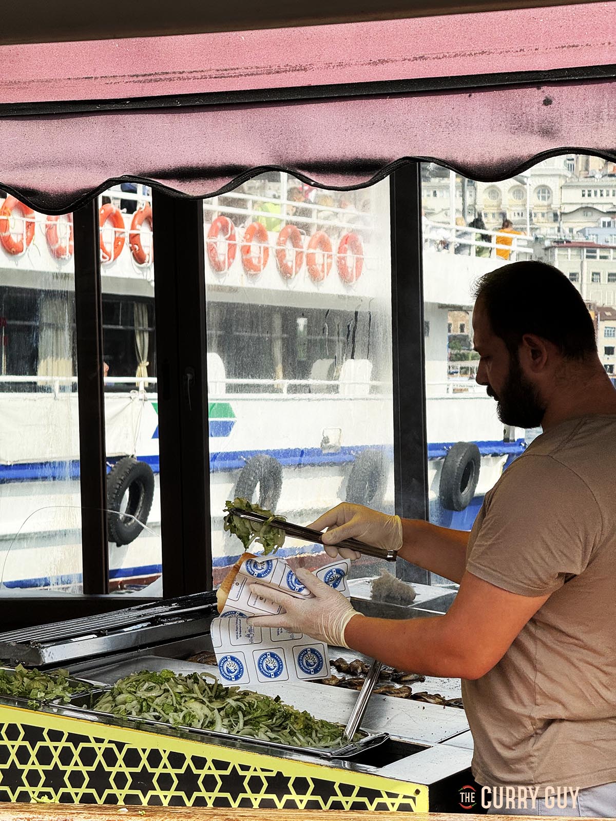 A chef preparing a fish sandwich for a customer.