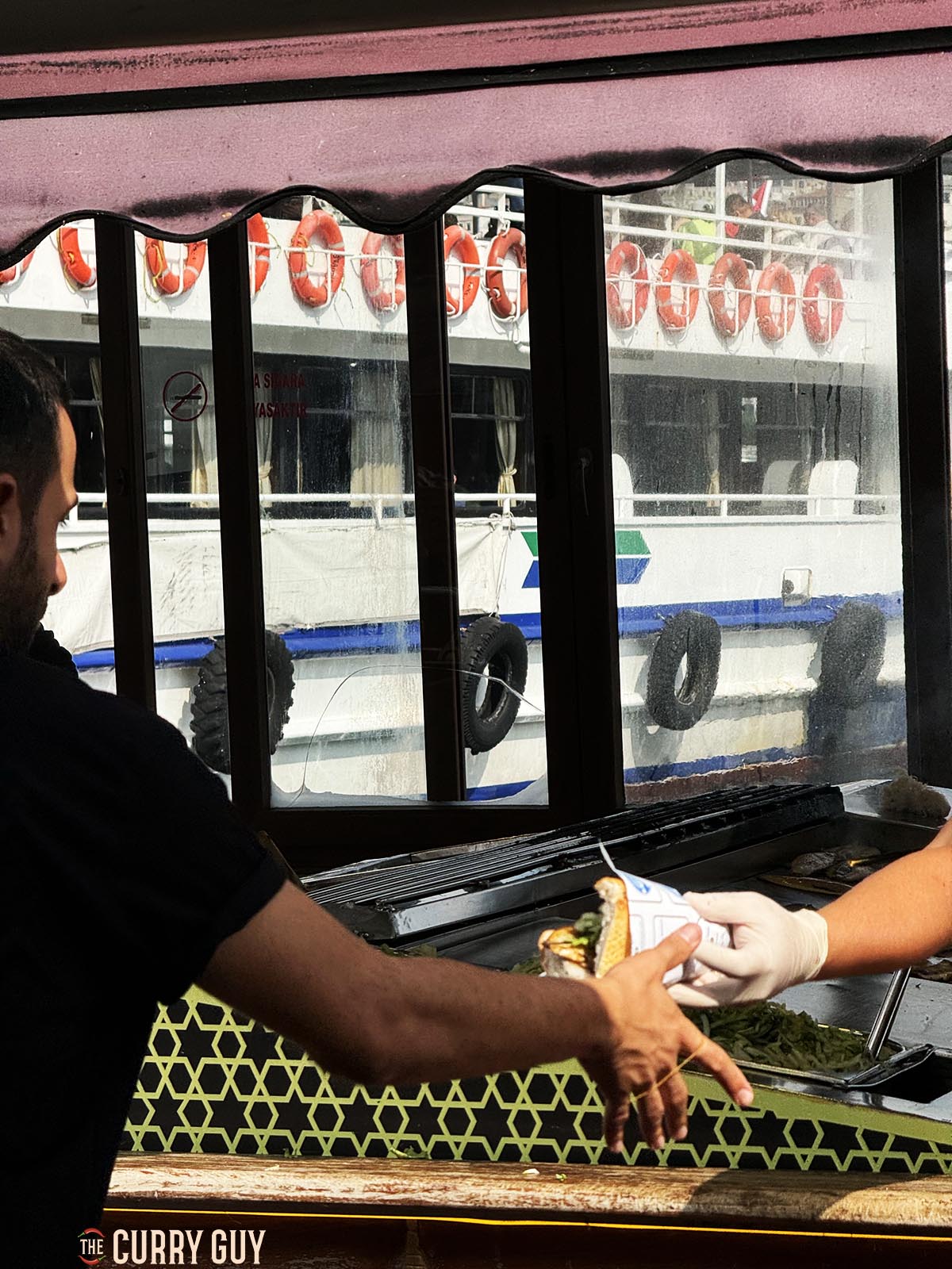 Passing a prepared fish sandwich from the boat to a server on the land.