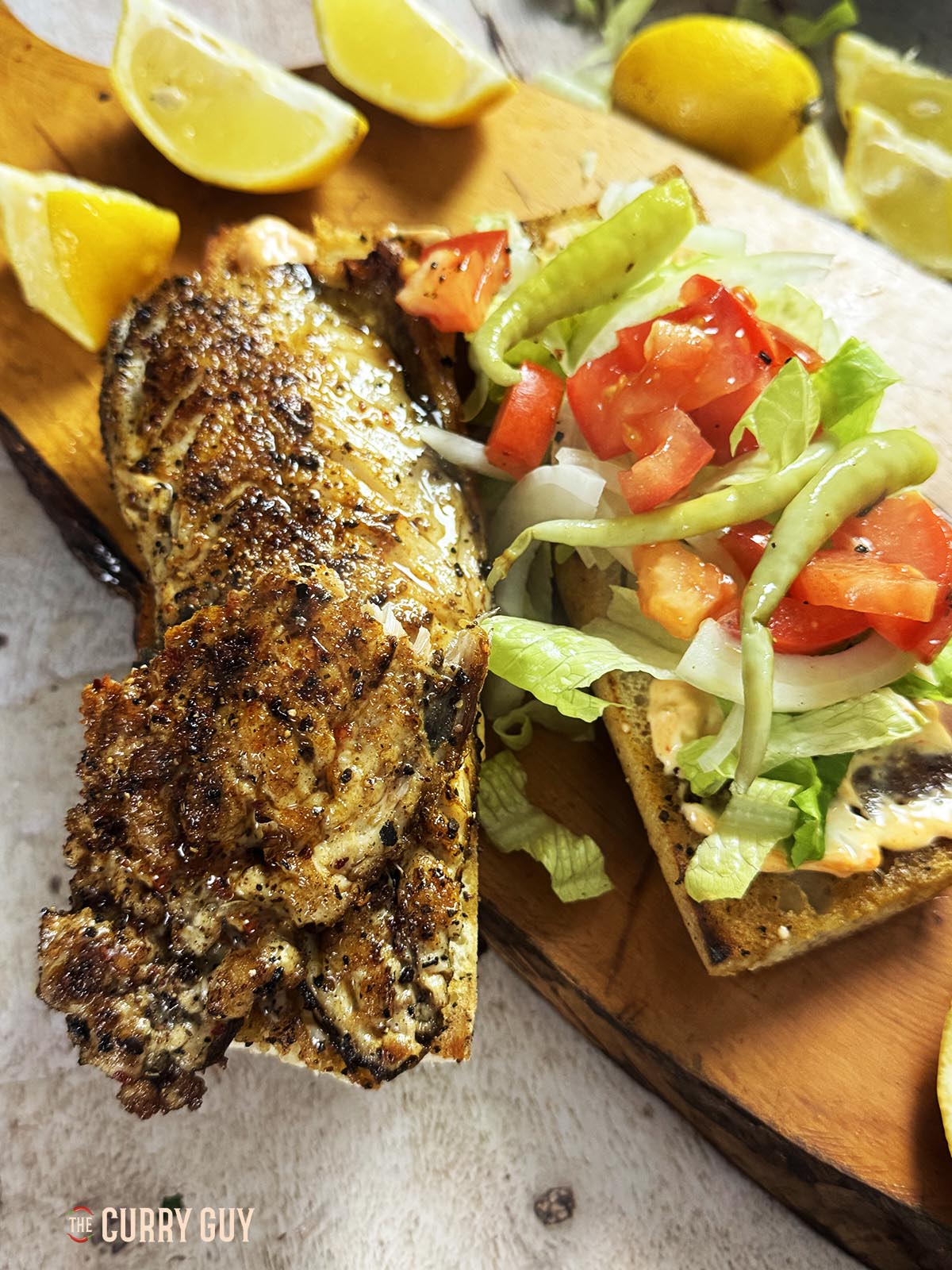Building the fish sandwich by adding fish, sauce and vegetables to the toasted bread.