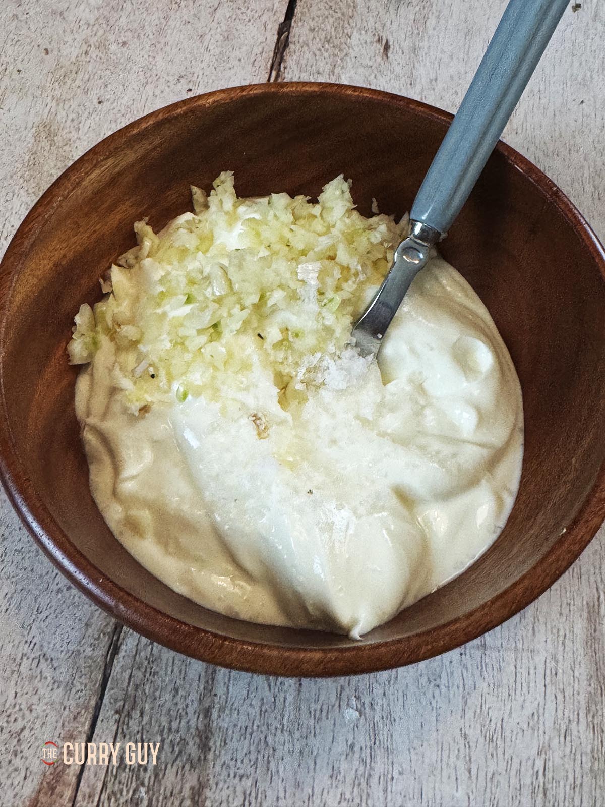 Whisking the yoghurt with the minced garlic and seasoning with salt to taste.