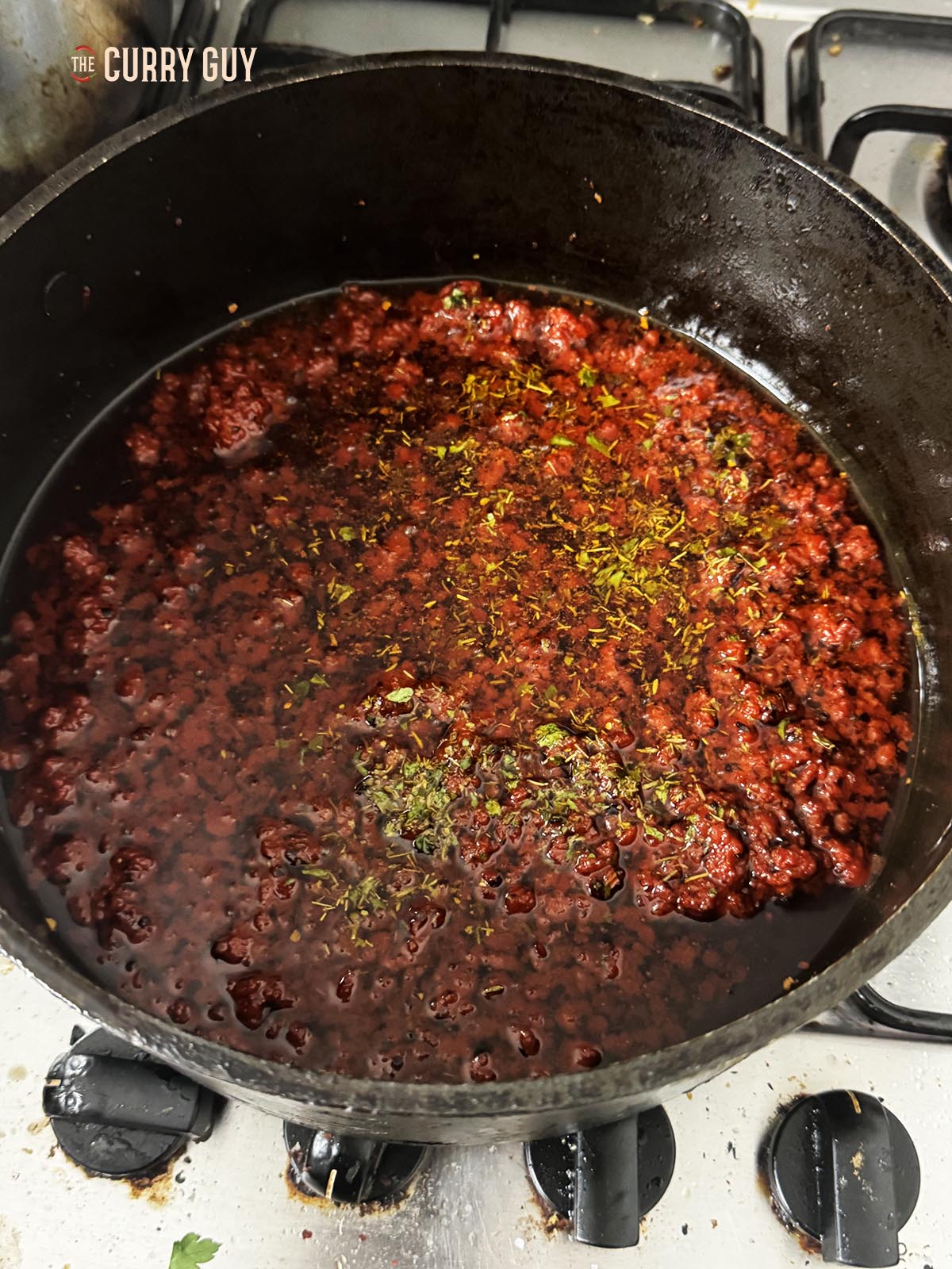 Adding the dried herbs to the sauce.