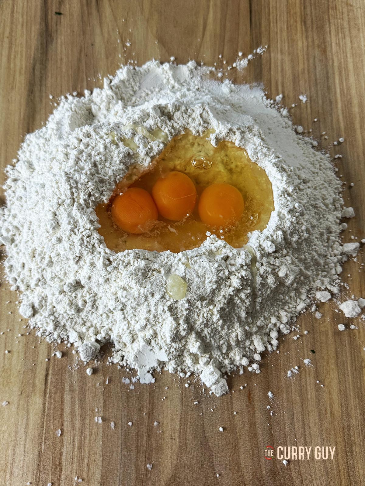The flour and eggs on a countertop, ready to start preparing the dough.