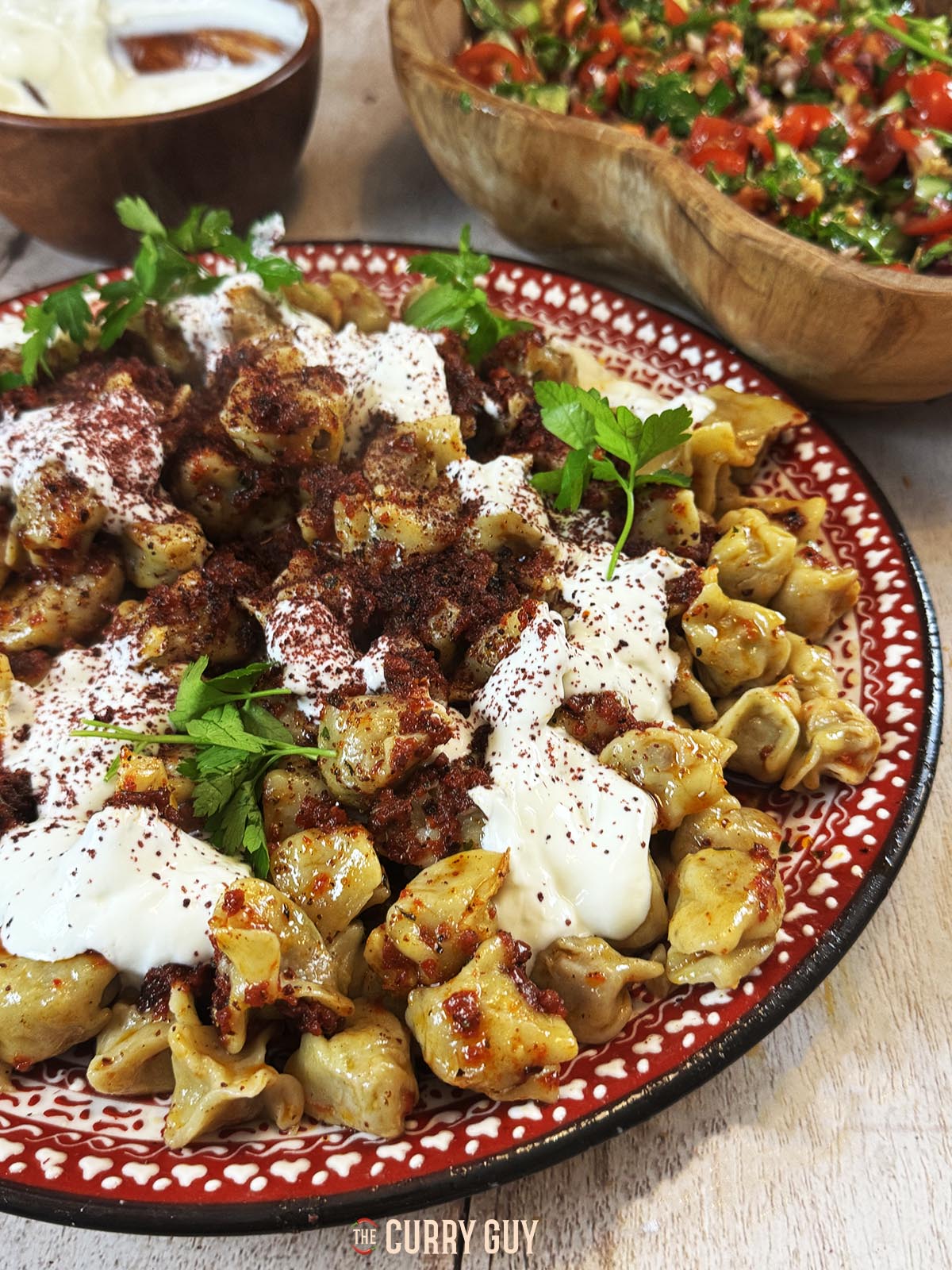 The finished manti recipe on a serving plate served with the pepper oil and garlic yoghurt.