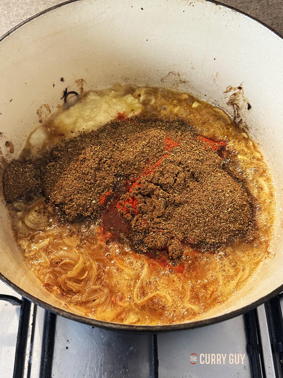 Adding ground spices to the onions in the pot.