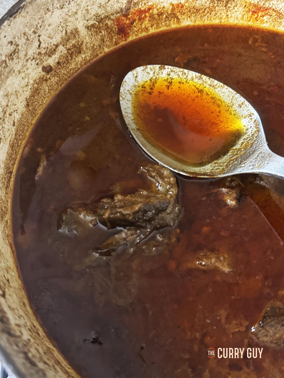 Skimming the oil off the top of the sauce.