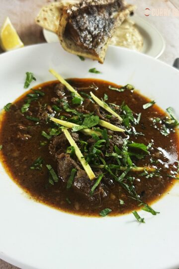 Beef nalli nihari in a serving bowl, garnished with julienned ginger, green chillies and chopped coriander.