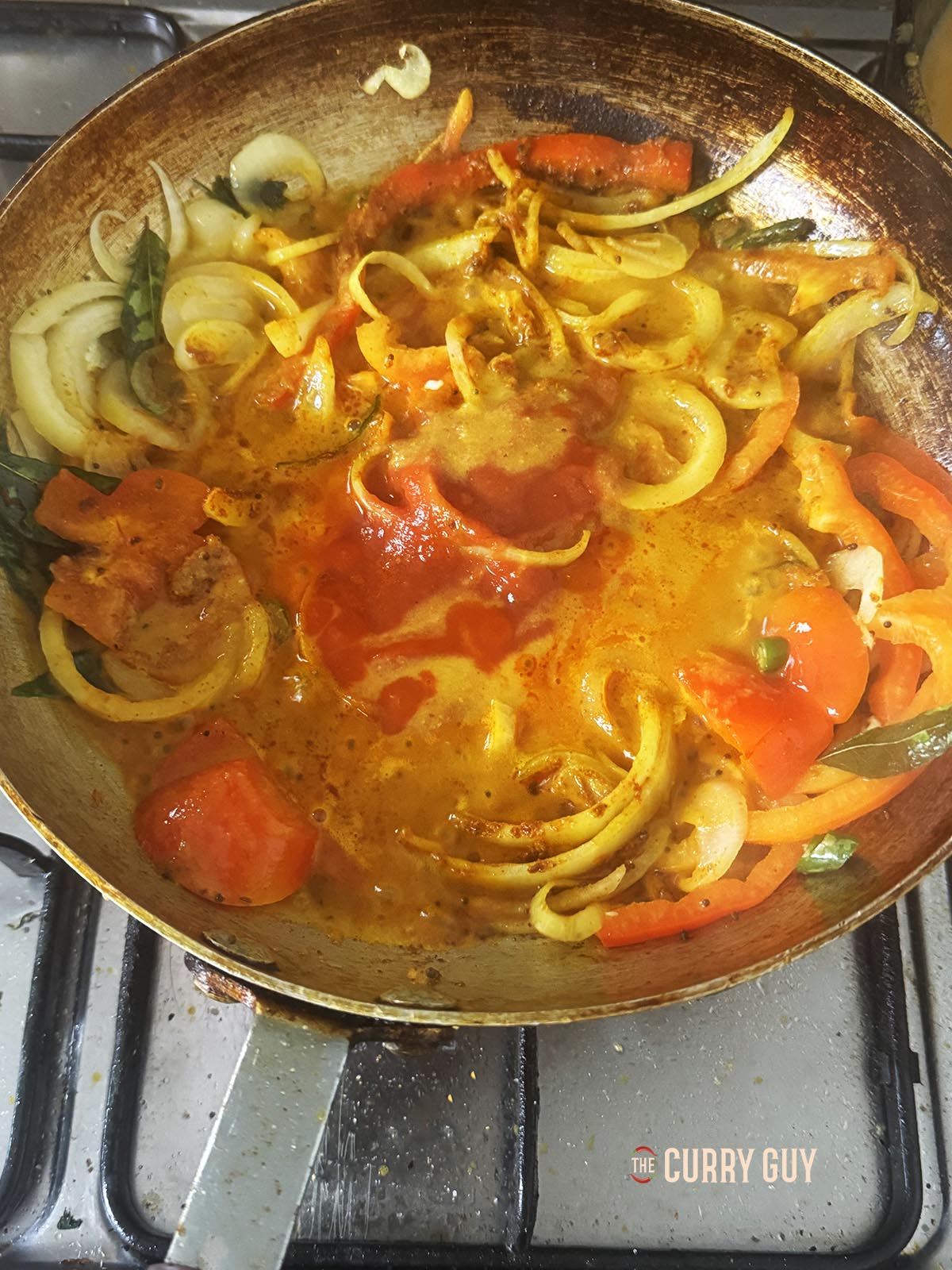 Adding a ladleful of the base curry sauce.