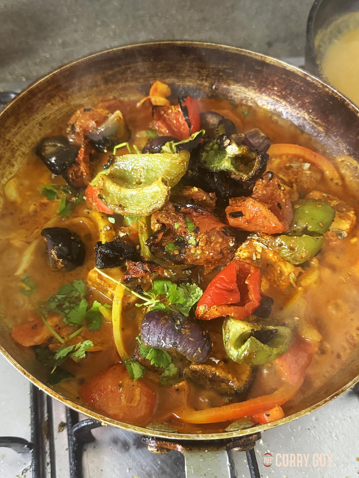 Adding the grilled vegetables to the pan.