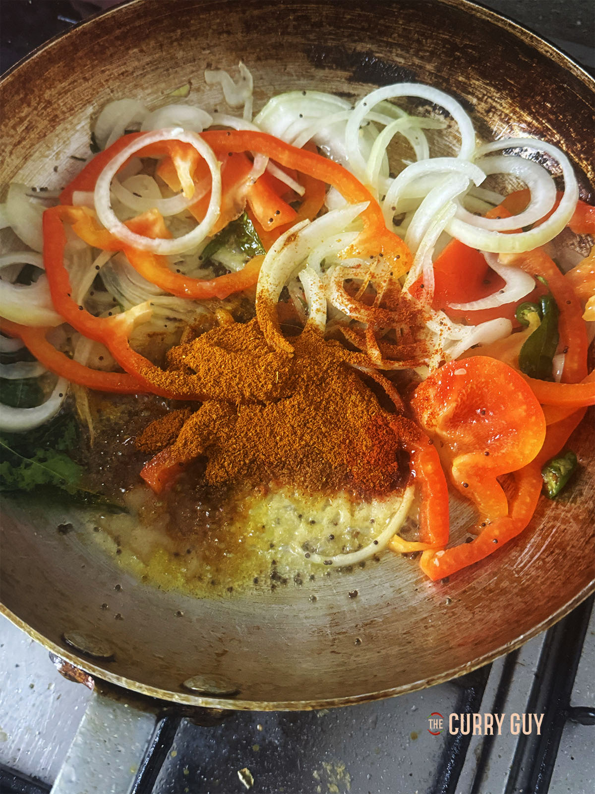 Stirring the ground spices into the onion, bell pepper and chillies.