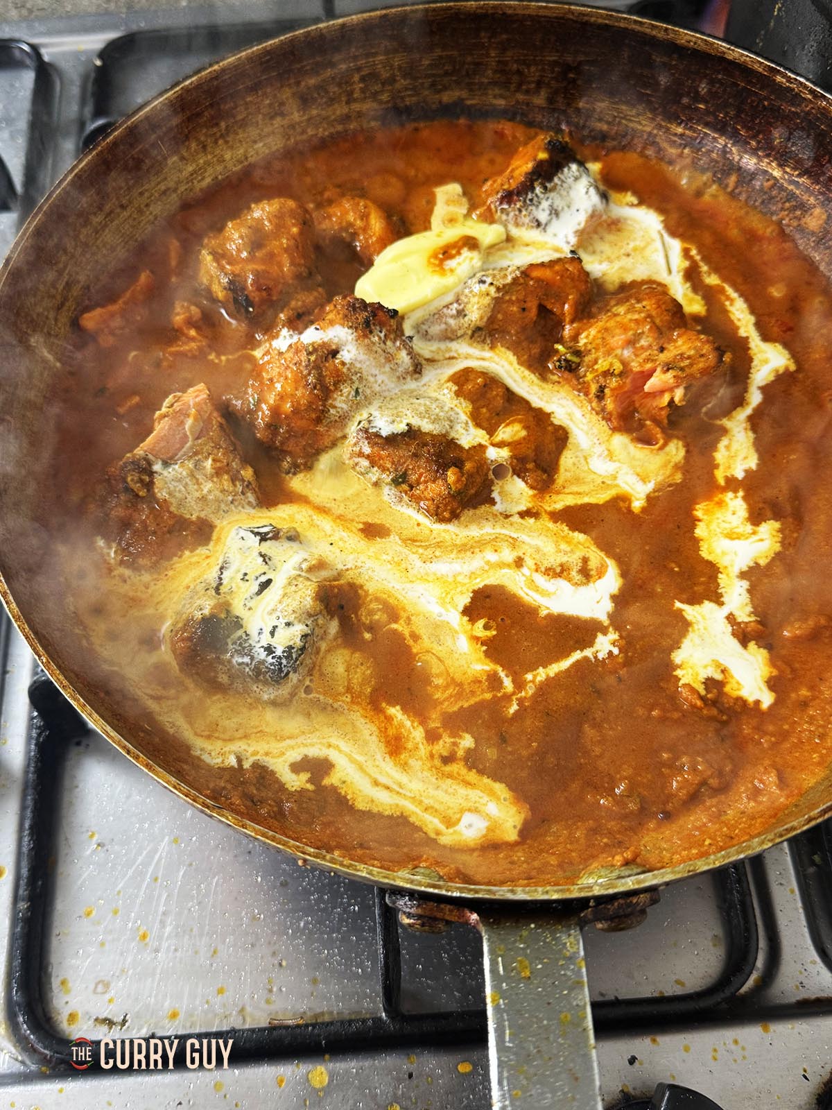 Pouring the cream and butter into the curry.