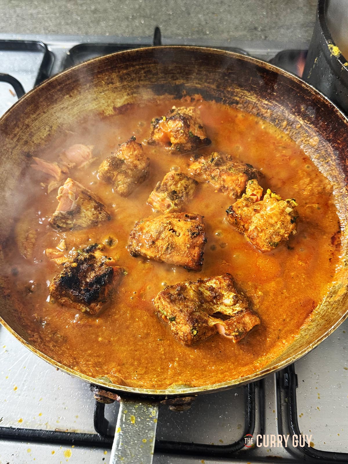 Stirring the salmon tikka into the pan.